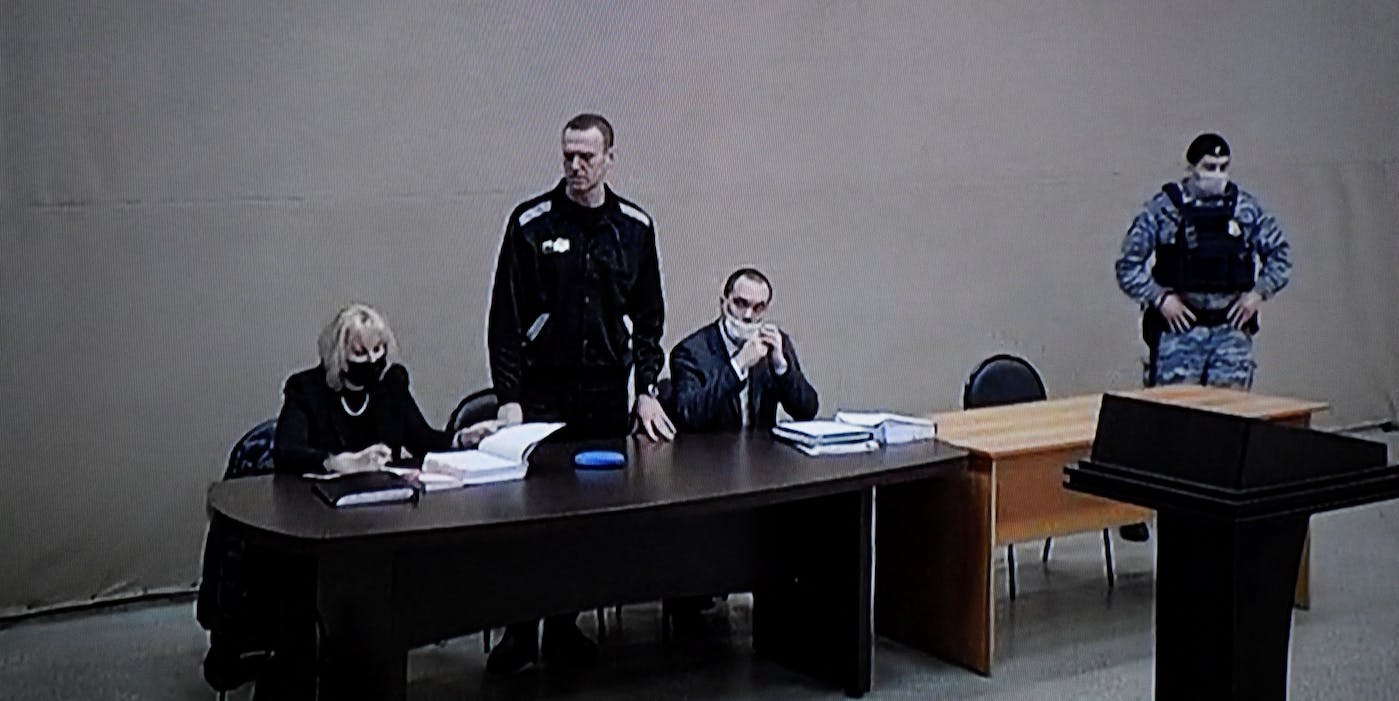 A photograph taken from a TV screen during live broadcast of the court hearing at the penal colony N2 shows Kremlin critic Alexei Navalny (C) during the court hearing at the penal colony N2, on the first day of his new trial, in the town of Pokrov on February 15, 2022. - A new trial against jailed Kremlin critic Alexei Navalny began on February 15, 2022 inside the prison colony where he serves a two-and-a-half year prison term for violating parole, in a case that could see his sentence extended by more than a decade. (Photo by Alexander NEMENOV / AFP) (Photo by ALEXANDER NEMENOV/AFP via Getty Images)