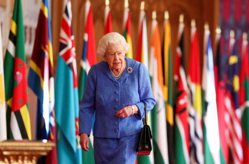 In this undated image released on March 6, 2021, Queen Elizabeth II walks past Commonwealth flags in St George's Hall at Windsor Castle, to mark Commonwealth Day, in Windsor, England.