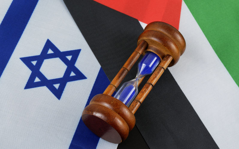 Hourglass on Israel and Palestine flags close up.